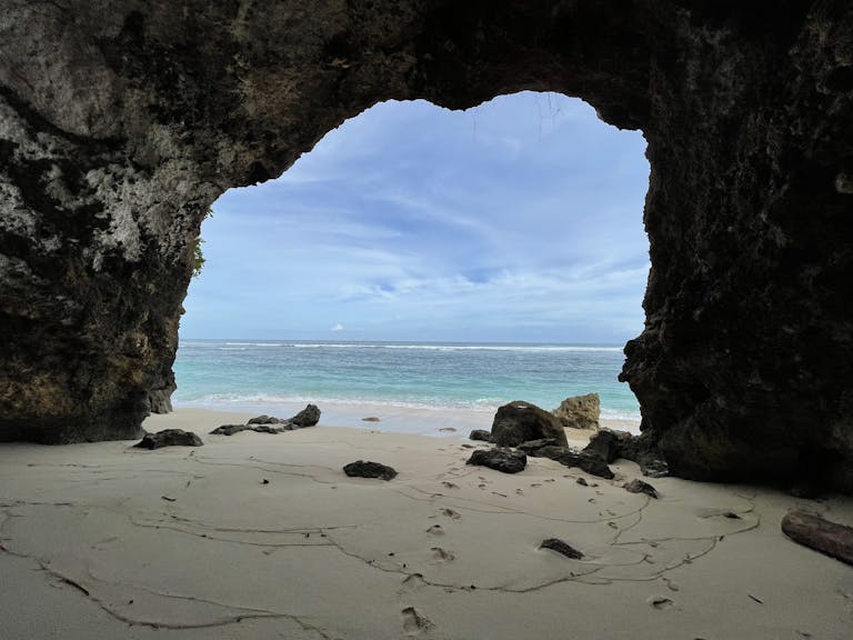 Explore a stunning beach scene through a natural cave opening in Bali, Indonesia.